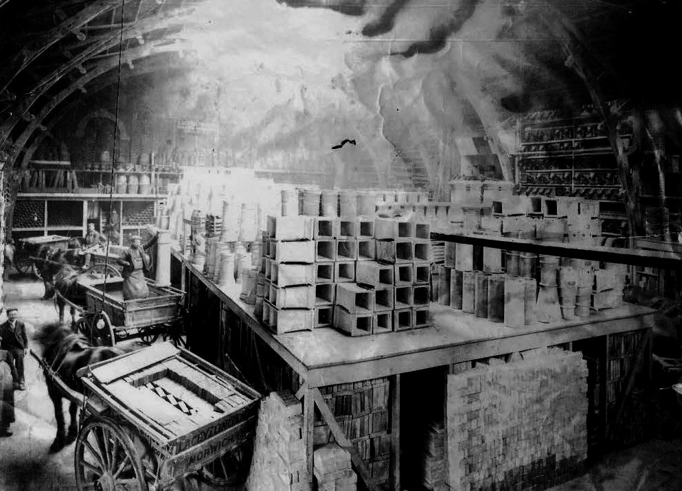 A black and white photograph showing the rink as a builders merchants warehouse. There are various construction materials on shelves and a horse and cart in the left bottom corner.