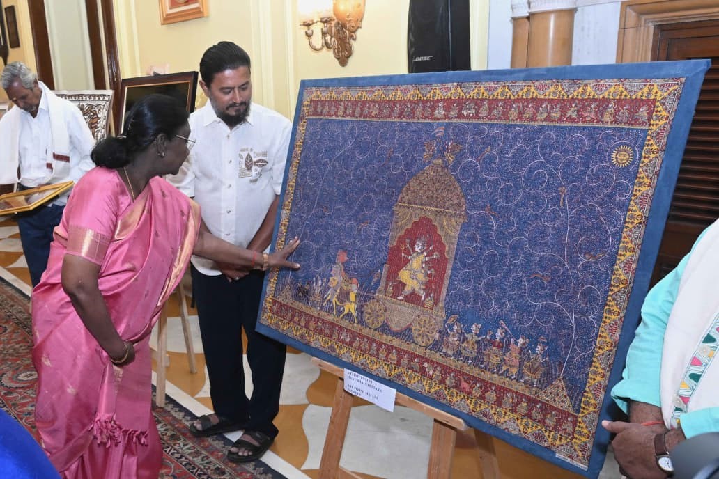 A picture of artisans holding up a mata ni pachedi to someone