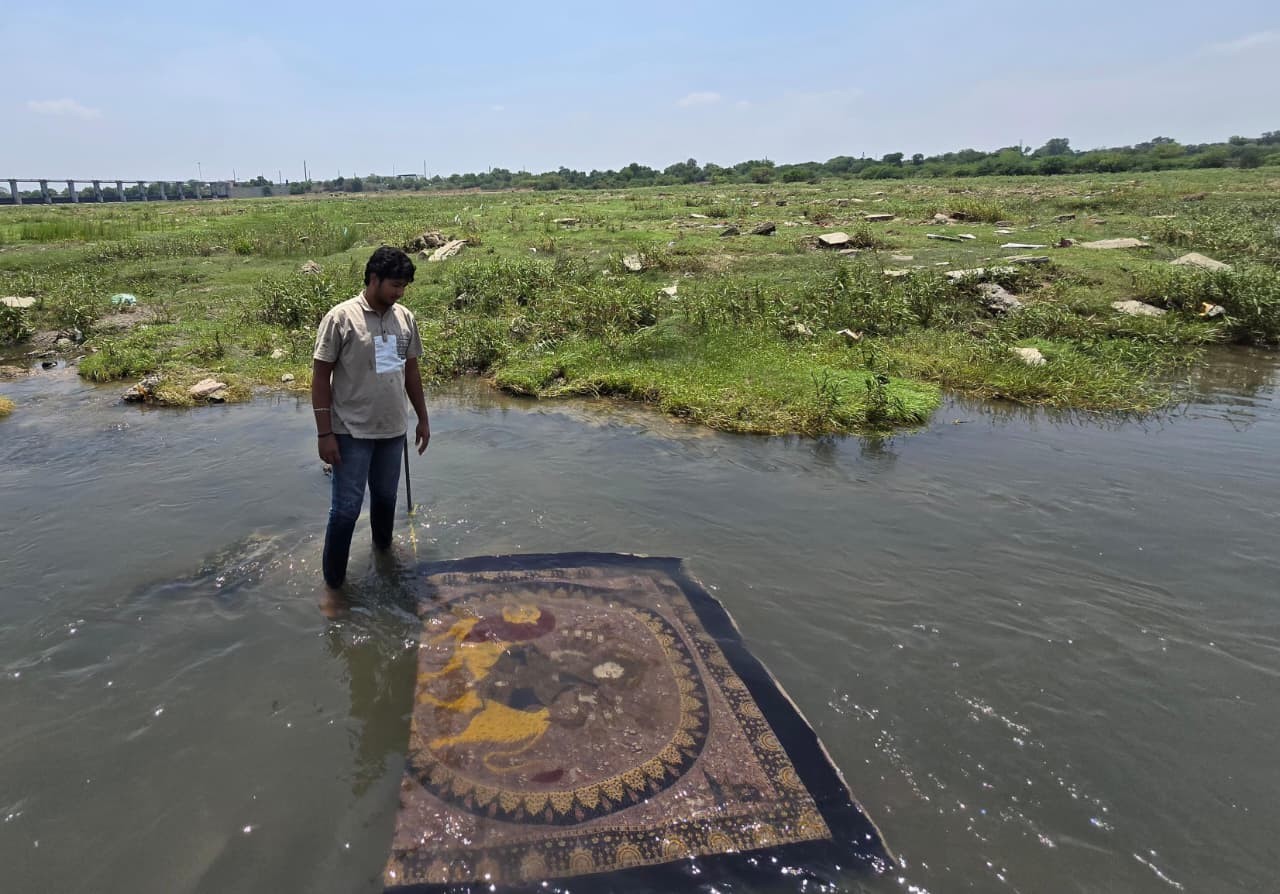A photo of an artist with the mata ni pachedi in the water with grass in the background.